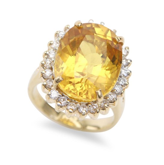 A SAPPHIRE AND DIAMOND RING - Featuring an oval yellow sapphire weighing 15.93cts, within a border of round brilliant cut diamonds t...