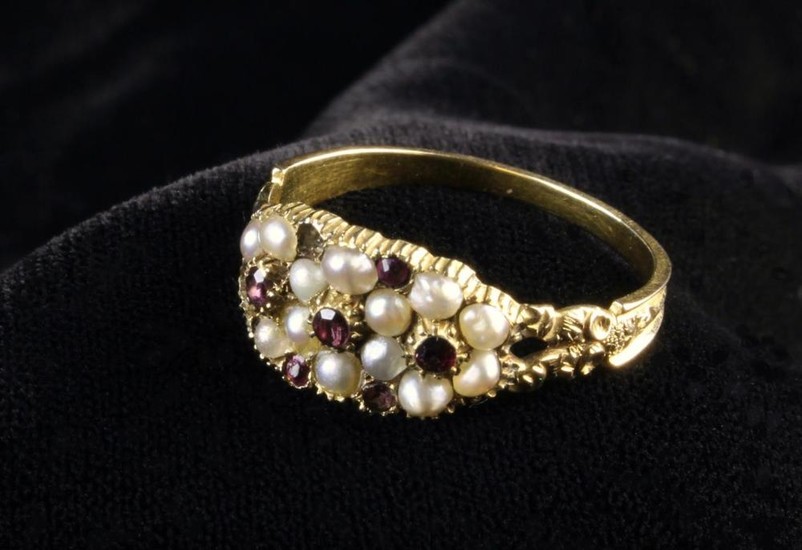 A Victorian Gold Ring set with a cluster of seed pearls and garnets, the split shoulders carved with