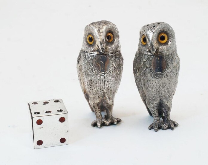 A Victorian novelty silver and enamelled pepper shaker in the form of a die, London, 1889, Thomas Johnson II, 2.5cm x 2.5cm; together with two novelty silver plated peppers in the form of owls, with coloured glass eyes, 8cm high (3)