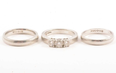 A diamond three stone ring and two platinum wedding bands.