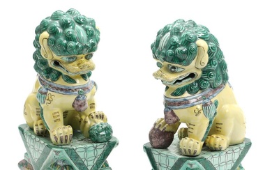 A pair of Chinese porcelain figures in shape of lions seated on...