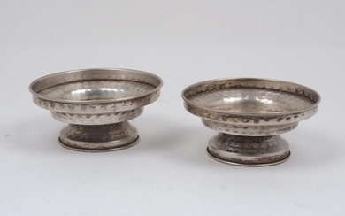 A pair of hammered white metal candlestick holders, of stepped,...