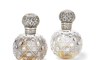 A pair of silver mounted glass perfume bottles, London, 1900, Frances Douglas, the globular, hobnail pattern cut glass bodies with glass stoppers to repousse silver screw caps decorated with floral and foliate scroll motifs, 13.5cm high (2)