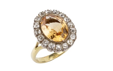 A topaz and diamond cluster ring, the oval central orange-brown...