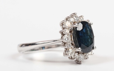 A white gold, sapphire and diamond oval cluster ring, claw set with the oval cut sapphire within a s