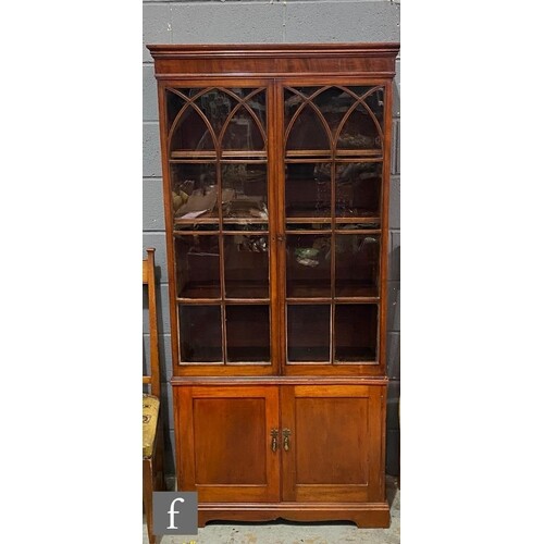 An early 20th Century inlaid mahogany bookcase, the interior...