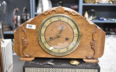 An early 20th century oak mantel clock with pendulum and key.
