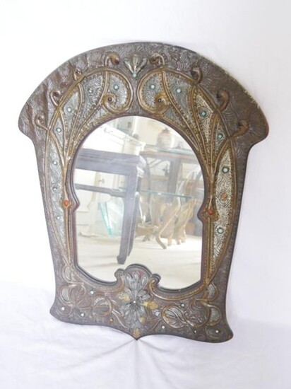 Arched mirror in a rich frame in slight relief of repoussé brass and pewter plants with blue glass cabochons.