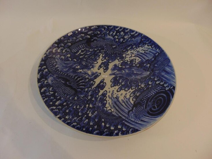 Large deep dish with far eastern blue and white decoration of two dragons facing each other, late 19th century, porcelain, mark on the reverse, d. 60,5 cm.
