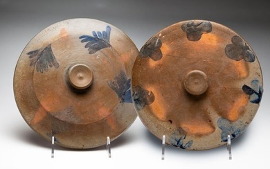 TWO FREEHAND DECORATED STONEWARE CAKE CROCK LIDS.