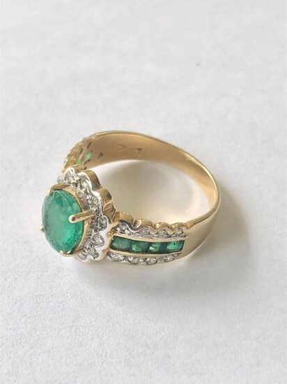 Yellow and white gold 750 thousandths ring set with an oval emerald netted with brilliants in the center shouldered by two lines of calibrated emeralds and four lines of brilliants 4 g, size 51 - Emerald 7.6 x 5.9 x 3.7 mm or about one carat.