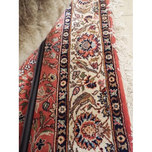 A large red ground rug with stylised decoration 115" x 80"