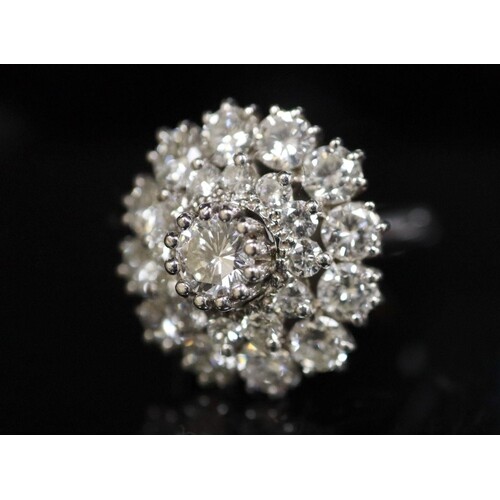 A modern 14ct white gold and diamond cluster ring, the centr...