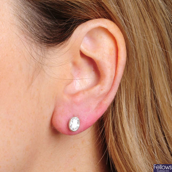 A pair of oval-shape diamond stud earrings.Total