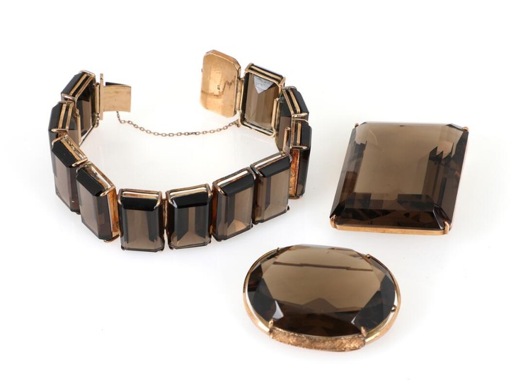 A smoky quartz jewellery set comprising a pendant set with an emerald-cut...
