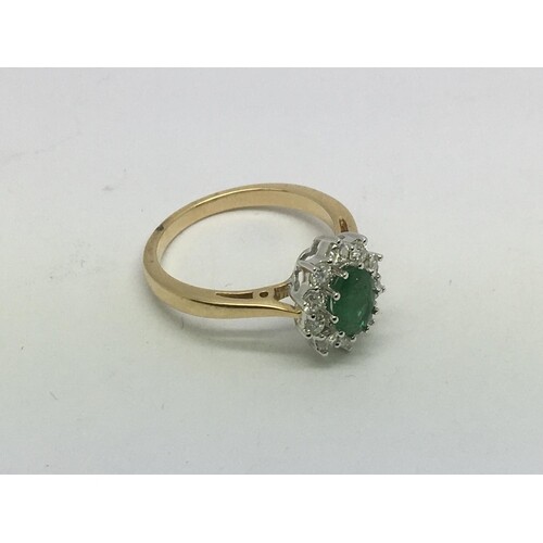 An 18ct gold oval cut emerald and diamond cluster ring. Emer...