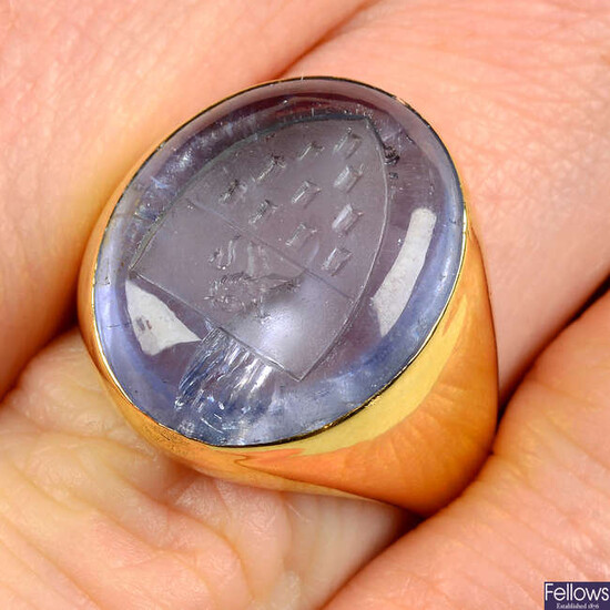 An 18ct gold sapphire cabochon ring, the sapphire with engraved heraldic device.