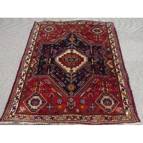 Tribal rugs; a Persian Qashqai red and blue ground rug, the ...