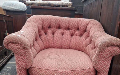 A TUB ARMCHAIR WITH A ROUNDED BUTTON UPHOLSTERED BACK, THE TURNED MAHOGANY FRONT LEGS ON BRASS