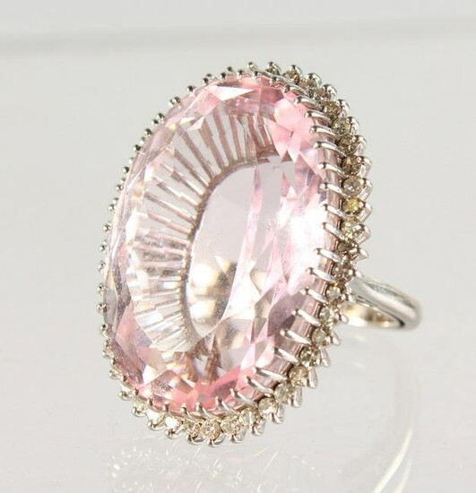 A VERY LARGE PINK OVAL STONE, surrounded by diamonds