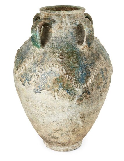 A large post-Sasanian green-glazed pottery storage jar, Iran, 8th-10th century, of baluster form on short foot, with tapering neck and rounded lip, the four handles joining the upper neck to the shoulder, the applied decoration with wavy bands and...