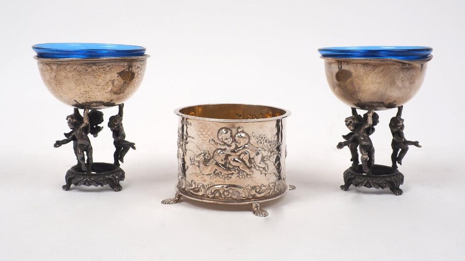 A pair of Italian silver pedestal salts, the plain rounded bowls supported by a ring of three cherubs, stamped 925 and signed Arte e Linea, both with blue glass liners, 9cm high, together with an Edwardian silver mustard/sugar, Chester, c.1903...