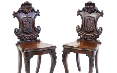 A pair of Victorian mahogany hall chairs with heavily carved...