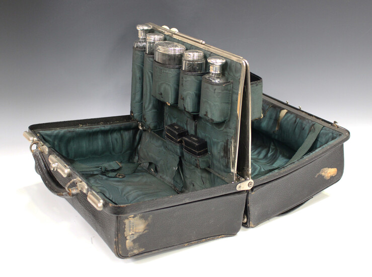 An Edwardian black leather Gladstone vanity bag, the interior fitted with five silver and cut glass