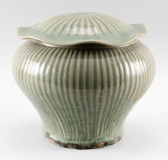 CHINESE CELADON STONEWARE COVERED JAR In inverted pear form, with lotus leaf-form cover and ribbed body. Height 10". Diameter 10.5".