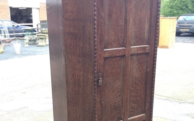 A 50s oak wardrobe with moulded cornice above a fluted...