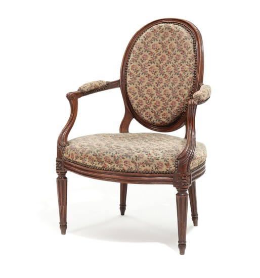 A French walnut Louis XVI armchair, curved armrests, fluted legs. Late 18th century.