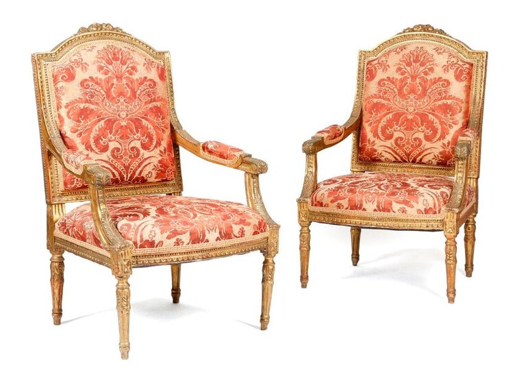 A PAIR OF GILTWOOD FAUTEUILS IN LOUIS XVI STYLE LATE 19T CENTURY each with a padded back, seat and armrests, covered in damask fabric, the moulded frames carved with leaves and flowers (2)