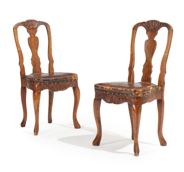 A pair of 18th century elmwood Rococo chairs carved with mussels and foilage, upholstered with patinated studded leather. (2)