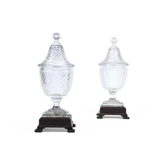 A pair of large Continental cut-glass urns, domed covers and associated carved wood stands, 20th century