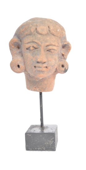 A pre Columbian head of stand. A terracotta / pottery carved head, with naïve facial features and elongated ear lobs. Mounted on a later stand. Approximately 9cm.