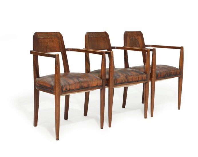 A set of three circa 1900 mahogany Art Noveau armchairs, back carved with foliage, upholstered with patinated leather fitted with nails. (3)