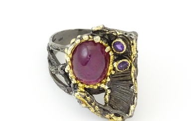 A silver ring set with ruby cabochon and two amethysts, with...