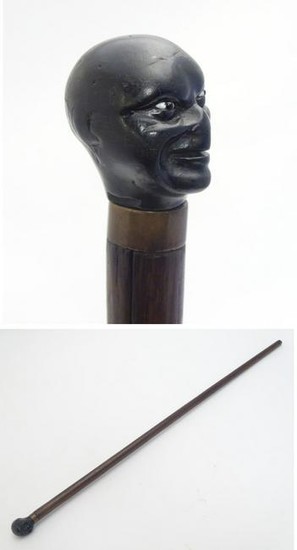A walking stick / cane with a carved ebonised pommel