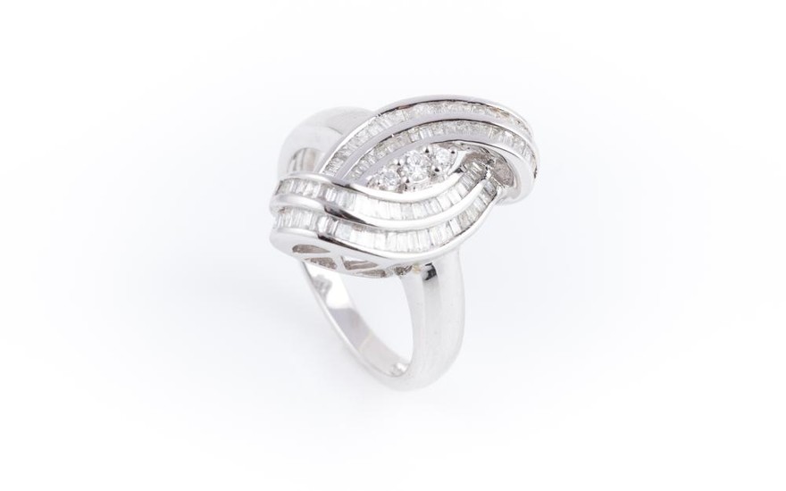 AN 18CT WHITE GOLD DIAMOND DRESS RING; centring 3 graduated round brilliant cut diamonds to double surround of channel set baguette...