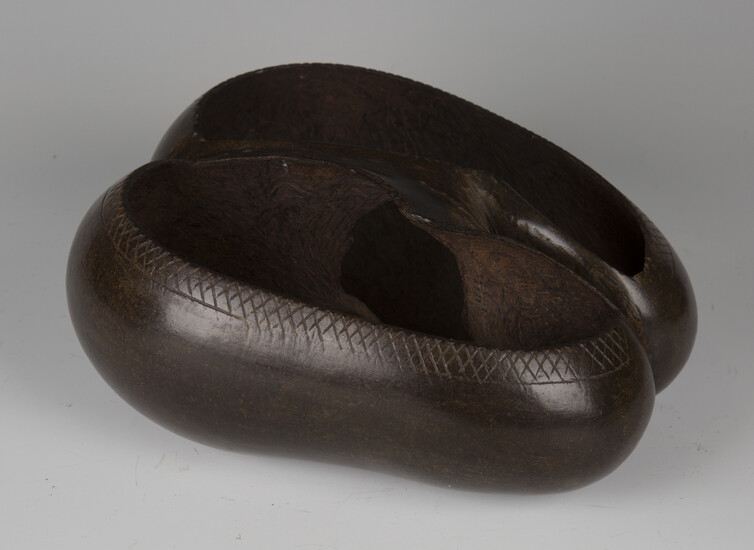 An early 20th century coco-de-mer nut, carved as a two-section bowl with central handle, length 27cm
