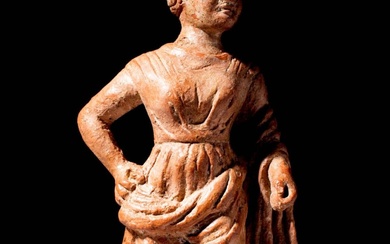 GREEK TERRACOTTA FIGURINE OF A STANDING DRESSED WOMAN