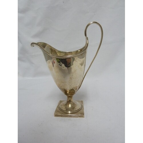 A George III silver cream jug of helmet form with reeded rim...