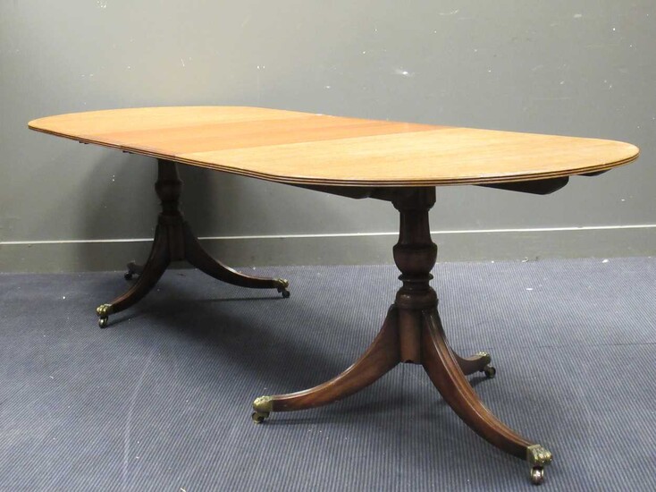 A reproduction mahogany extending dining table, on twin column supports each with three swept