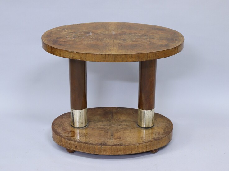TABLE D'APPOINT de forme ovale en bois exotique, à double plateau en placage de loupe, réuni par deux colonnes lisses à bagues métalliques. Il repose sur quatre pieds boules.