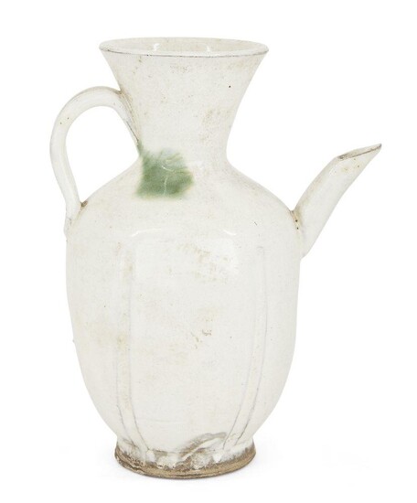 A Chinese white-glazed 'green splash' ewer, Northern Song dynasty, with a six-lobed body rising to a flaring neck, set on one side with a slightly curving neck opposite a strap handle, covered in white slip with a splash of green to the shoulder...