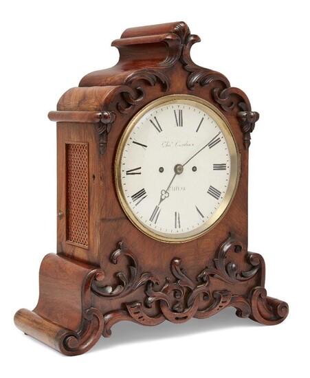 A Victorian walnut eight day mantel clock, late 19th century, the walnut case with relief carved scrolling foliate decoration on scrolling base, having pierced brass side panels and reverse door, the painted circular dial with Roman numerals and...