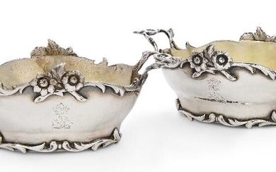 A pair of George IV silver salts/sweetmeat dishes by Paul Storr, London, 1827, of oval form with twin floral handles and applied floral and foliate scroll decoration to feet and rims, gilded interiors, both engraved with crest surmounted by an...