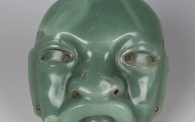 A pre-Columbian Olmec style carved green jade mask, probably 900-450 BC, with pierced holes to sides
