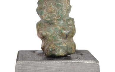 A pre Columbian stone carved figure. A figure depicting a stone seated figure of small proportions with naively carved features, mounted on a later base. Approximately 6cm tall.