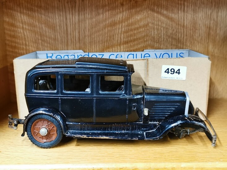 An early (c. 1930) model of a four door saloon car with bakelite body on a pressed metal chassis and clockwork motor with right hand drive